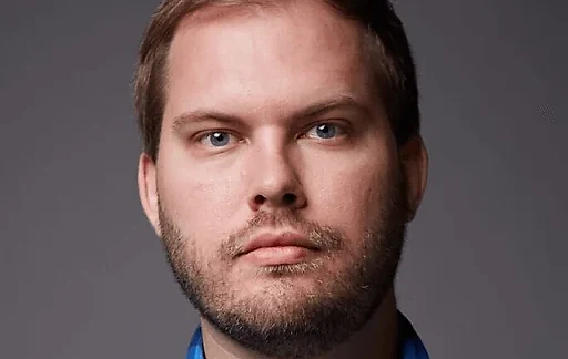 Mathew Hager in a close studio portrait on a plain grey backdrop.